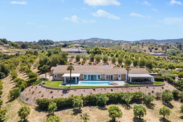Modern villa with swimming pool and terracotta roof in rolling Mediterranean countryside with olive groves